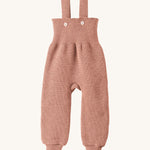 Disana organic merino wool dungarees in rose on a cream background.