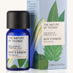 Don't Stress pure essential oil blend  in a blue glass bottle in front of a decorative blue cardboard box.