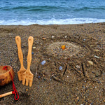 A mandala shape in the sand created using the bamboo tools for the Dr Zigs beach creativity set. The Kit is placed beside the mandala on the sand
