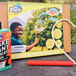 Dr Zigs eco-friendly flatpack hand wand bubble kit laid out on a piece of slate on some green grass