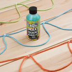 Close up of the Dr Zigs 10x concentrated bubble mixture on a wooden floor next to some coloured rope bubble blowers