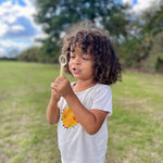Child blowing bubbles with the small hand wand from the mini bubble kit