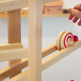 Close up of a hand rolling the Fagus wooden spiral disc toy down a Fagus wooden marble run set