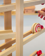 Close up of a hand rolling the Fagus wooden spiral disc toy down a Fagus wooden marble run set