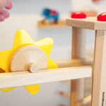 Close up of a hand rolling the Fagus spinning sun toy down a Fagus wooden marble run