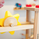 Close up of a hand rolling the Fagus spinning sun toy down a Fagus wooden marble run