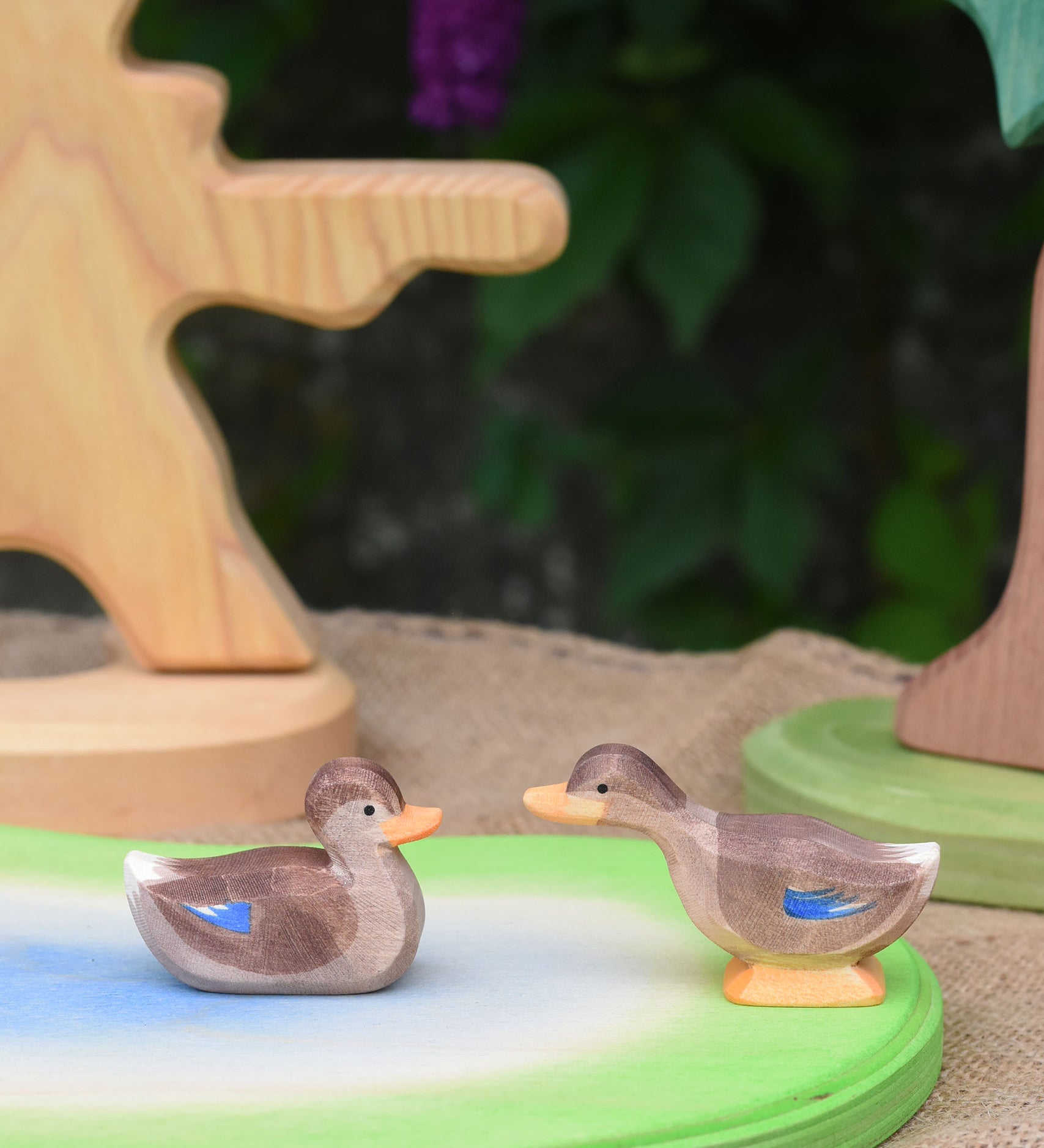 Two Ostheimer wooden ducks placed on a wooden pond scene piece.