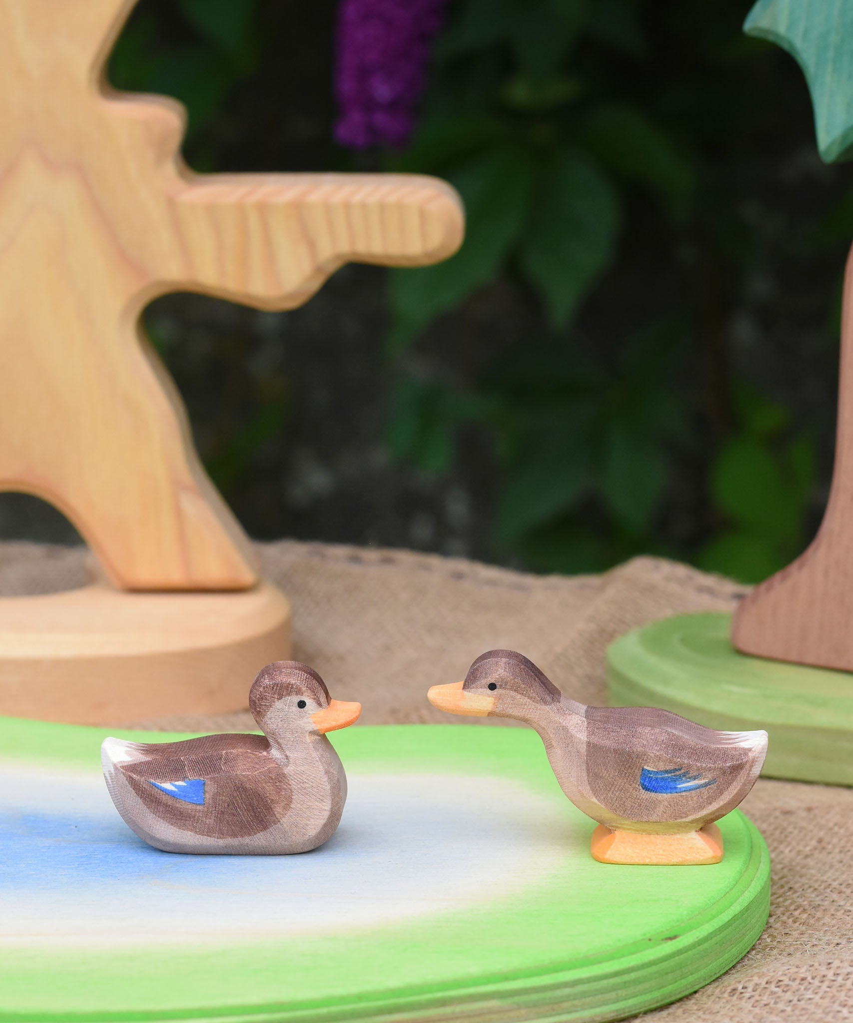 Two Ostheimer wooden ducks placed on a wooden pond scene piece.