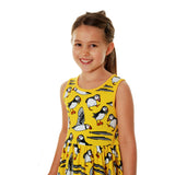 Girl stood on a white background wearing the DUNS Sweden organic cotton sleeveless gather skirt dress in the yellow puffin print