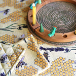 Duns Sweden organic cotton pot holder and tea towel in the bee yellow print on a tablecloth next to a celebration ring