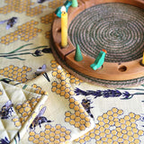Duns Sweden organic cotton pot holder and tea towel in the bee yellow print on a tablecloth next to a celebration ring
