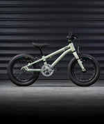 The Early Rider Belter 14" Kids Pedal Bike for 3-5 Years in sage green. The bike is shown in front of black garage doors. Babipur are official stockists of Early Rider. 