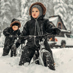 2 kids sat on some Early Rider 12 inch balance bikes in some deep snow