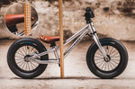 Close up of a child walking next to an Early rider charger balance bike