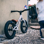 Young child riding the Early rider charger balance bike in some woods