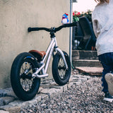 Young child riding the Early rider charger balance bike in some woods