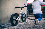 Young child riding the Early rider charger balance bike in some woods