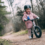 Close up of a child walking next to an Early rider charger balance bike