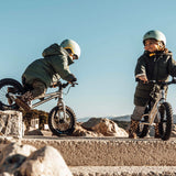 2 children riding Early Rider big foot balance bikes down a gravel path