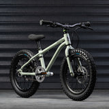A sage green coloured Early Rider X16 children's bike placed in front of black garage doors.