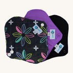 Three Earthwise Panty Liners in charcoal with flowers, purple and black.