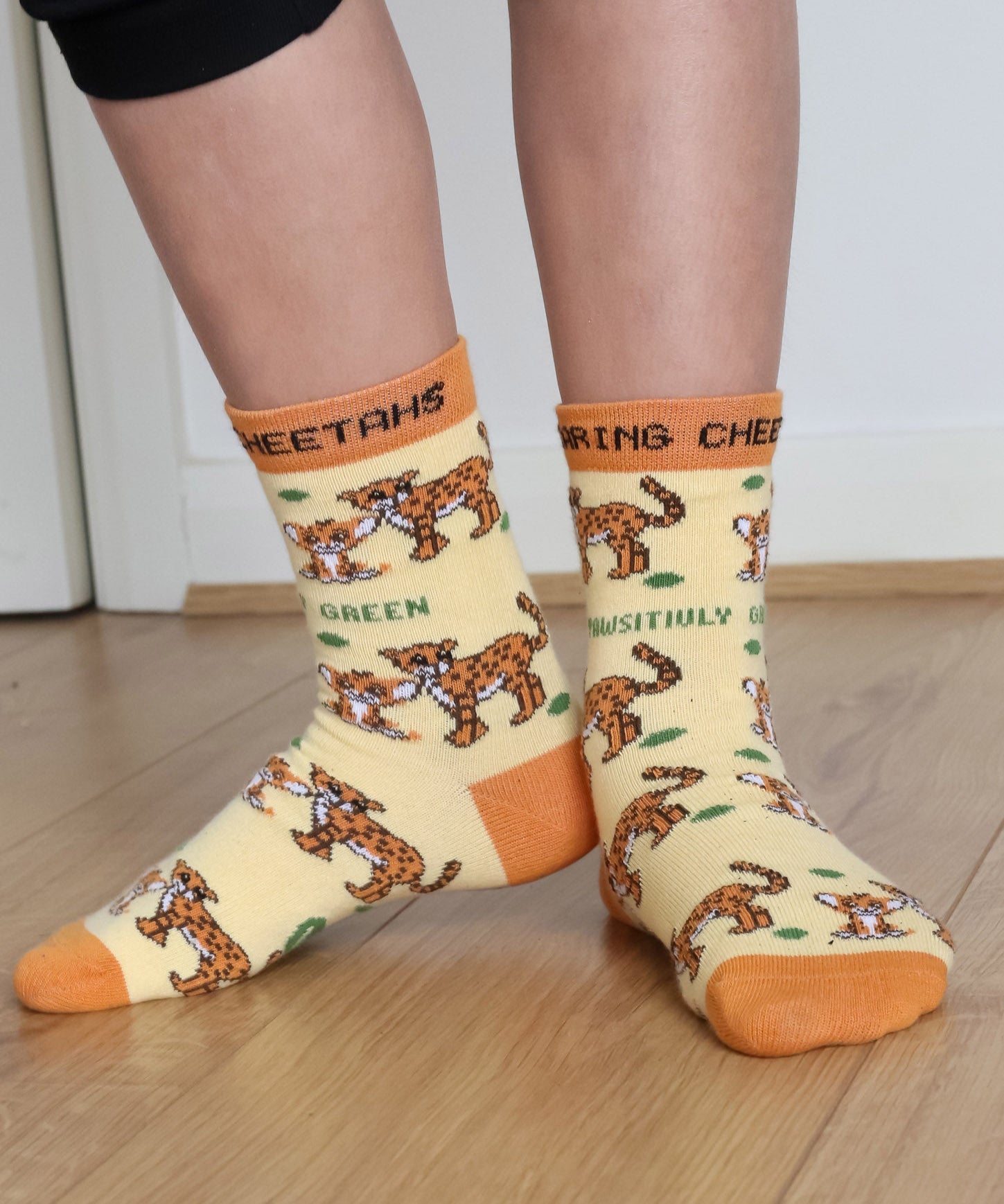 A close up of a child wearing the Eco Kiddies organic cotton cheetah socks showing the cute cheetah design and orange trim detail 