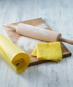 Ecoliving yellow compostable sponge kitchen roll next to a wooden board and rolling pin