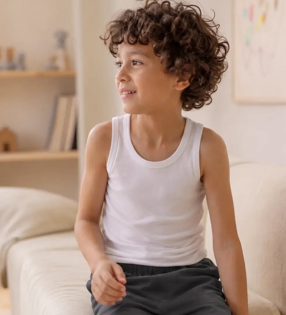 Boy wearing an Eco Outfitters organic cotton vest top for layering under school uniforms. 
