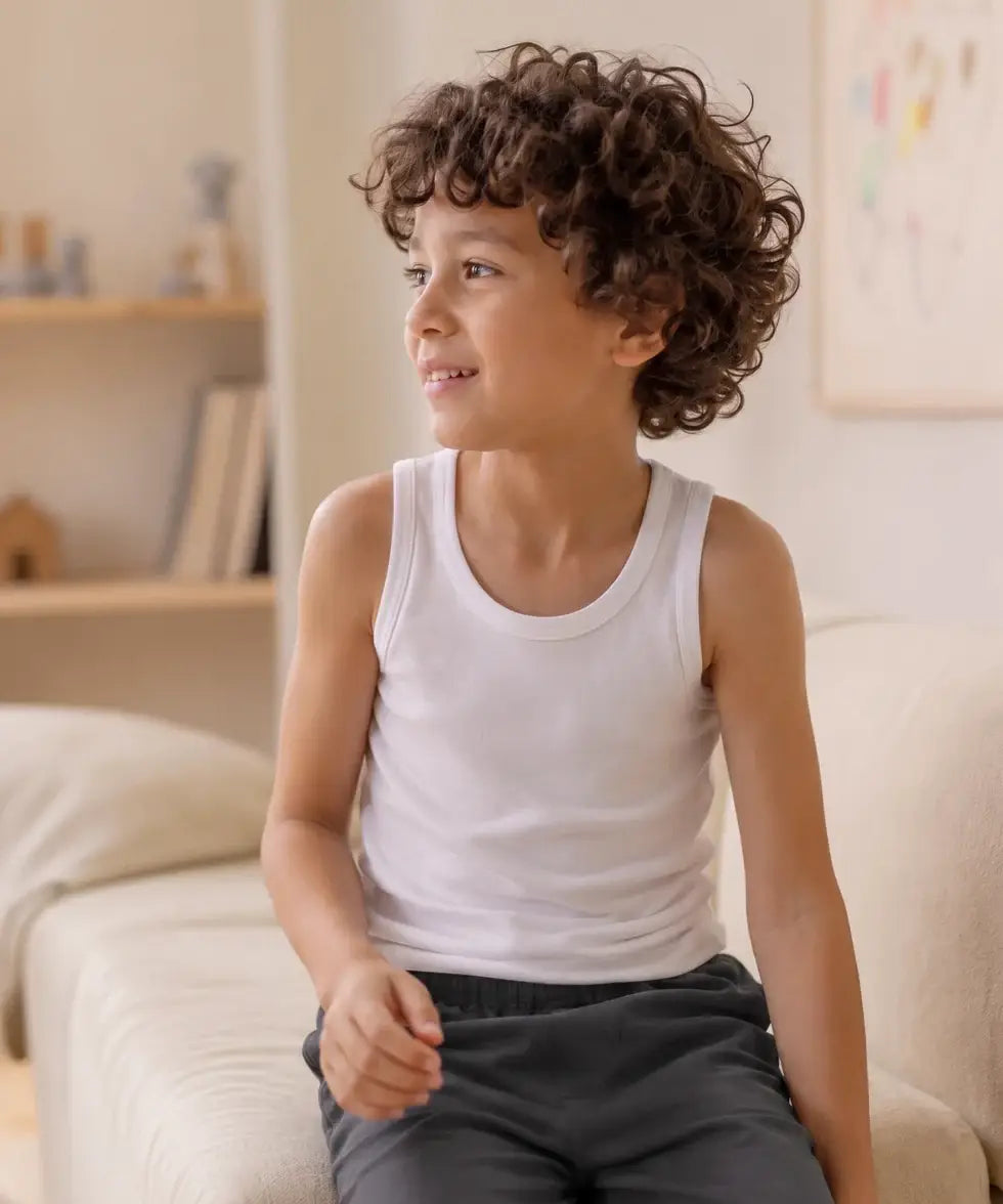 Boy wearing an Eco Outfitters organic cotton vest top for layering under school uniforms. 