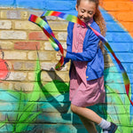 A little girl playing in the schoolyard, wearing the Eco Outfitters organic and fair trade cotton gingham summer dress and school cardigan in blue.