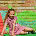 A little girl wearing The Eco Outfitters organic and fair trade cotton school summer dress in red gingham.