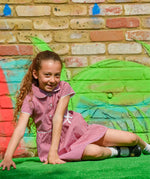 A little girl wearing The Eco Outfitters organic and fair trade cotton school summer dress in red gingham.