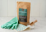 Ecoliving Bicarbonate Of Soda pictured next to green rubber gloves and a wooden scoop placed in a glass tub