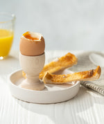 Eco Living wooden egg cup on a dish with an egg on top and 2 small slices of toast 