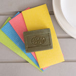 A bar of Ecoliving Organic Marseille Household Soap Bar placed on a pile of ecoliving compostable sponge cloths. 