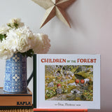 Children of the forest children's hardback book by Elsa Beskow placed on a wicker hamper on a stack of other Elss Beskow books.