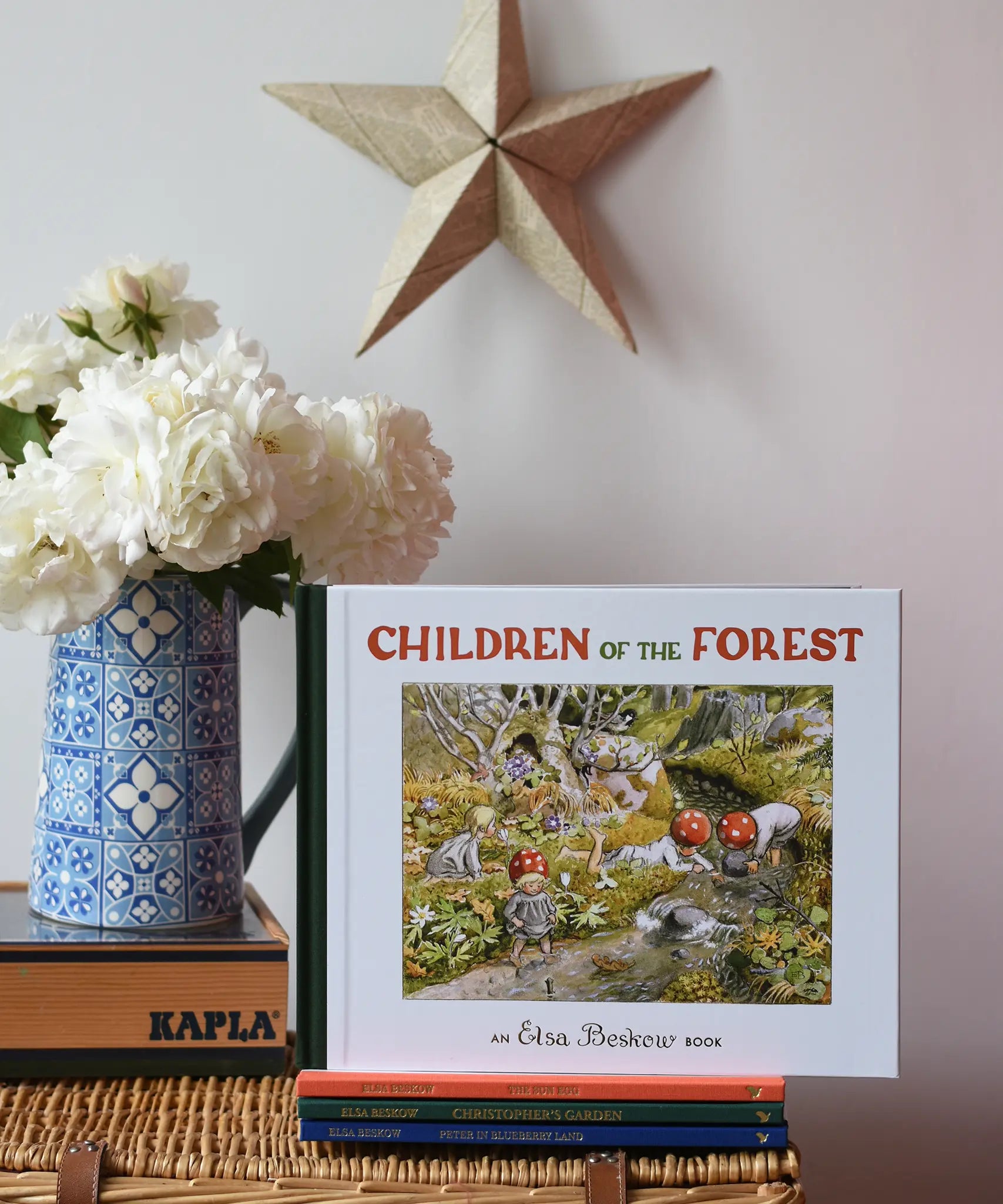 Children of the forest children's hardback book by Elsa Beskow placed on a wicker hamper on a stack of other Elss Beskow books.
