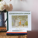 Christopher's garden children's hardback book by Elsa Beskow placed on a wicker hamper on a stack of other Elss Beskow books.