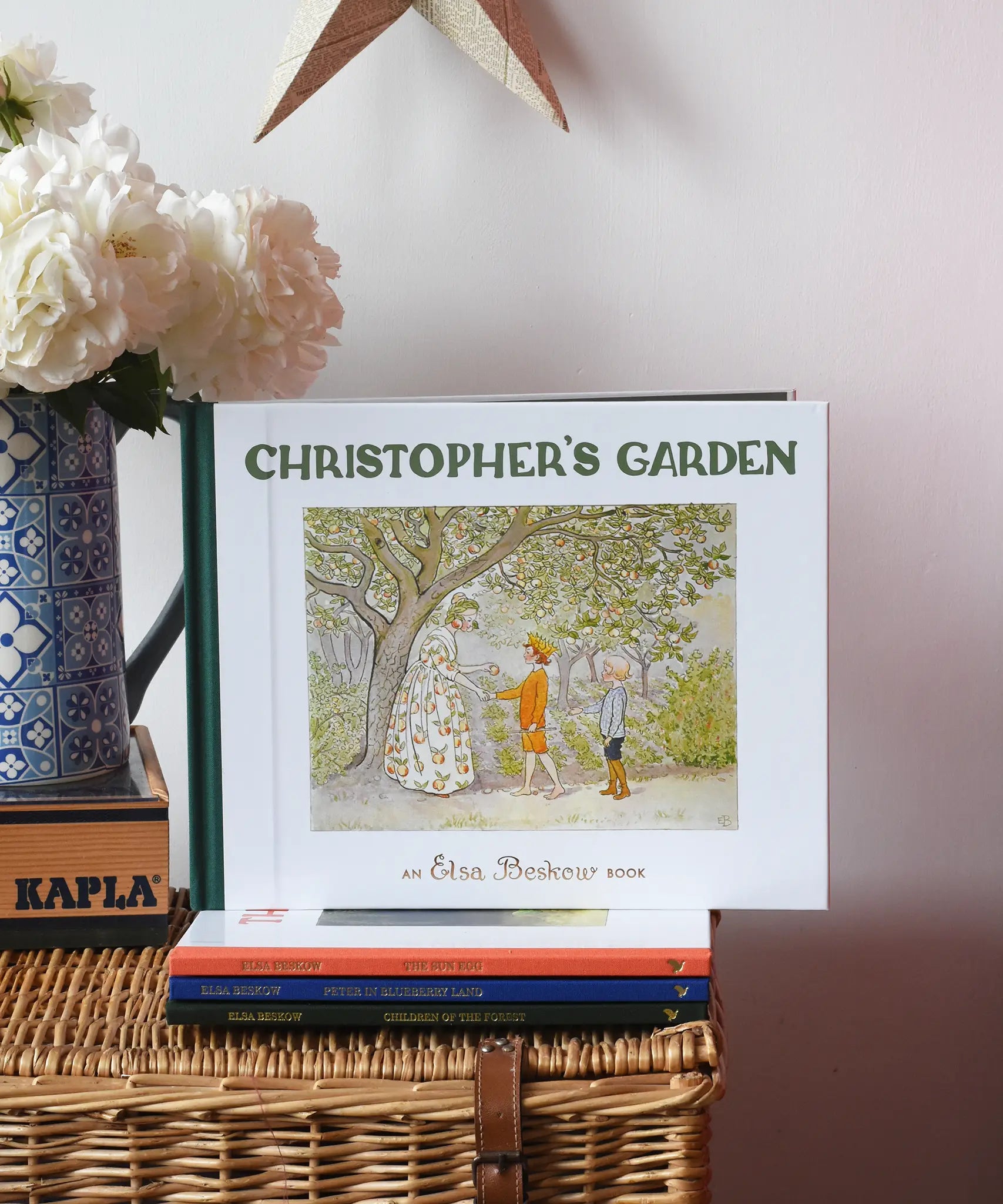 Christopher's garden children's hardback book by Elsa Beskow placed on a wicker hamper on a stack of other Elss Beskow books.