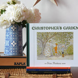 Christopher's garden children's hardback book by Elsa Beskow placed on a wicker hamper on a stack of other Elss Beskow books.