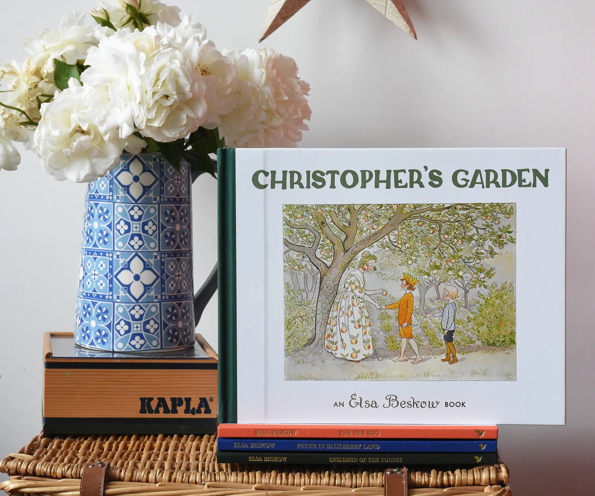 Christopher's garden children's hardback book by Elsa Beskow placed on a wicker hamper on a stack of other Elss Beskow books.