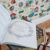 Inside page from the The World of Elsa Beskow: A Vintage Colouring Book placed on a stool in the Babipur playroom. Black and white line art coloring page. 