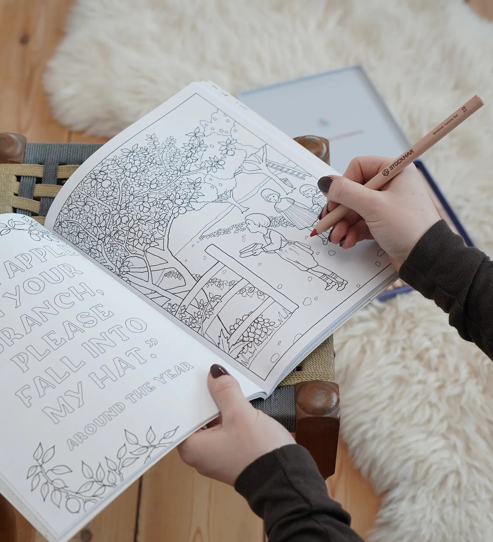 Inside page from the The World of Elsa Beskow: A Vintage Colouring Book. An adult's hand can be seen holding the book and a colouring pencil. Black and white line art coloring page illustration.