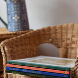 Stack of Elsa Beskow hardback children's books placed on a child's wicker chair. 