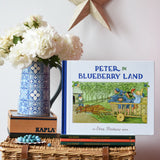Peter in Blueberry Land children's hardback book by Elsa Beskow placed on a stack of book on a wicker hamper