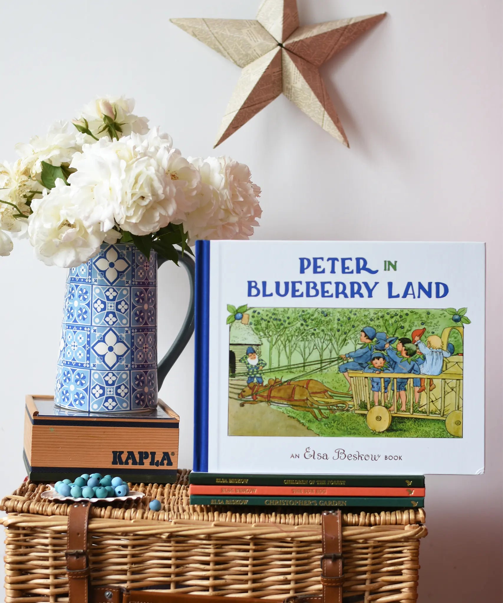 Peter in Blueberry Land children's hardback book by Elsa Beskow placed on a stack of book on a wicker hamper