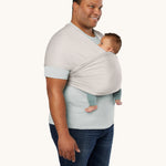 An adult is wearing the Ergobaby Aura Wrap Baby Carrier in Grey