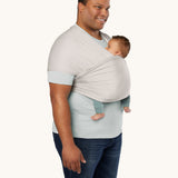 An adult is wearing the Ergobaby Aura Wrap Baby Carrier in Grey