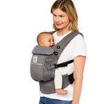 Woman with blonde hair and a white t-shirt wearing her baby in the Ergobaby Adapt  SoftFlex™ Mesh Baby Carrier in Graphite Grey. Side  view, white background. 