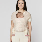 Mother carrying a baby in the Ergobaby aura sustainably knitted wrap carrier in dainty blooms in the frontal position